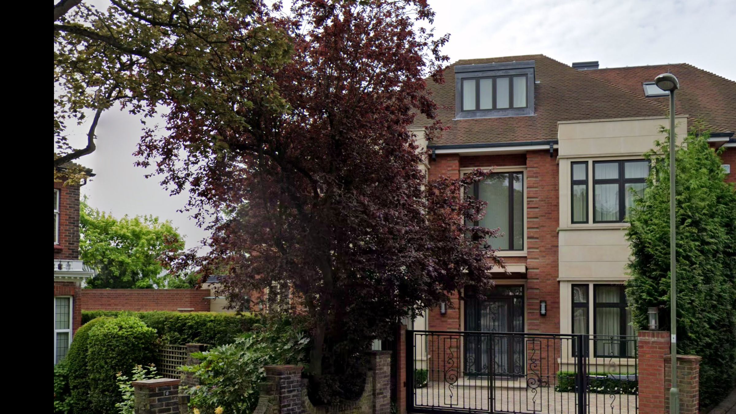 Front elevation of 12 Goodyers Gardens: red brick and pale stone, tall dark-framed windows and wrought-iron gates