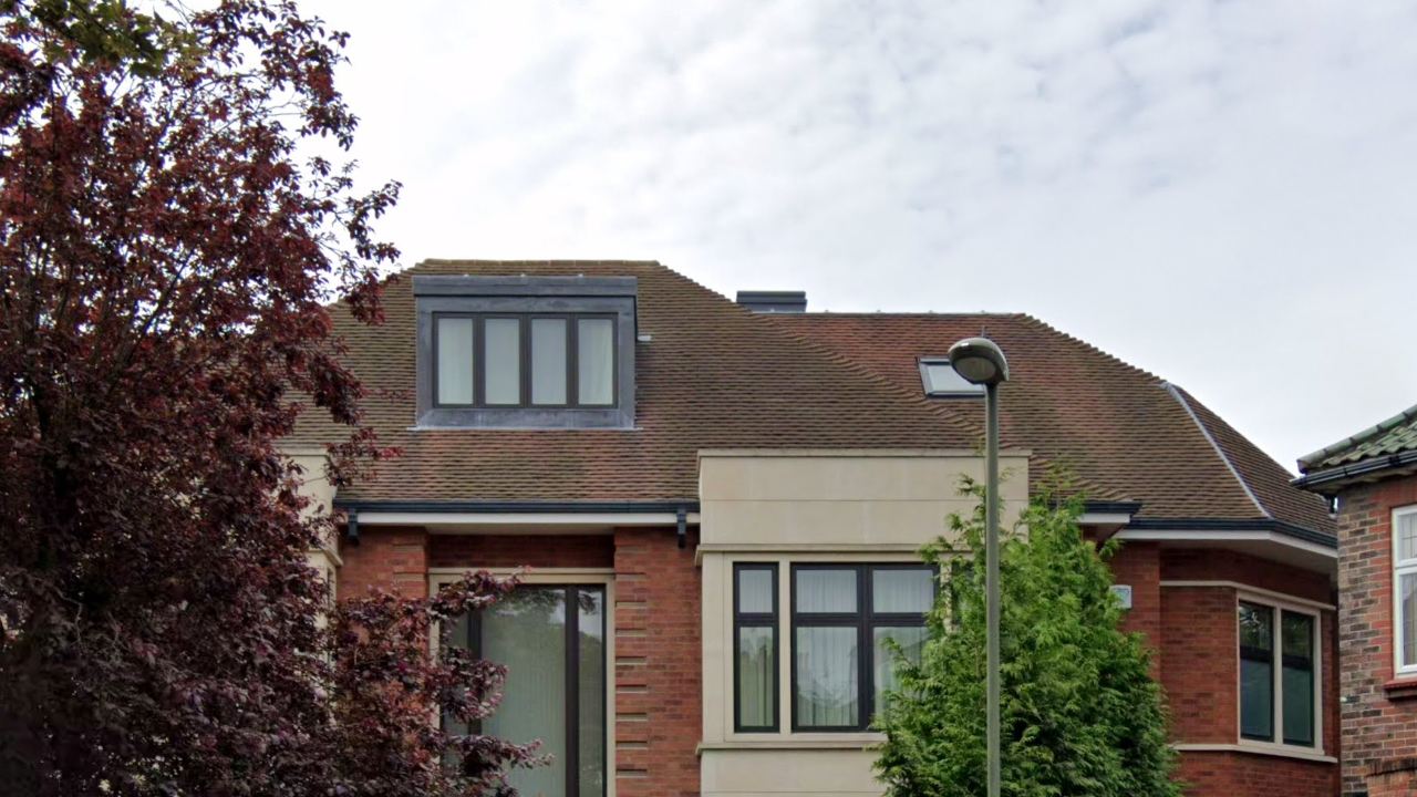 Upper façade with stone bay, dark-framed windows and dormer